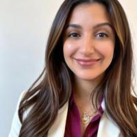 Yasamin Bolourian, a long brown haired woman smiling, wearing a purple shirt and white blazer